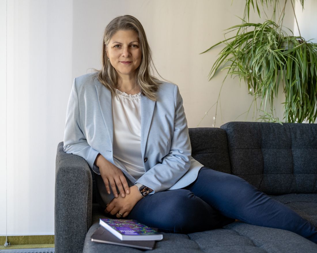 Žena v svetlom saku sedí na pohovke